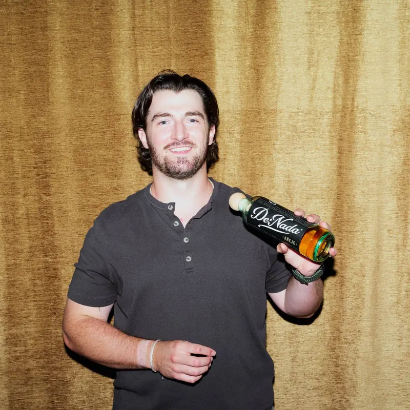 Danny holding a bottle of De Nada Añejo on his shoulder